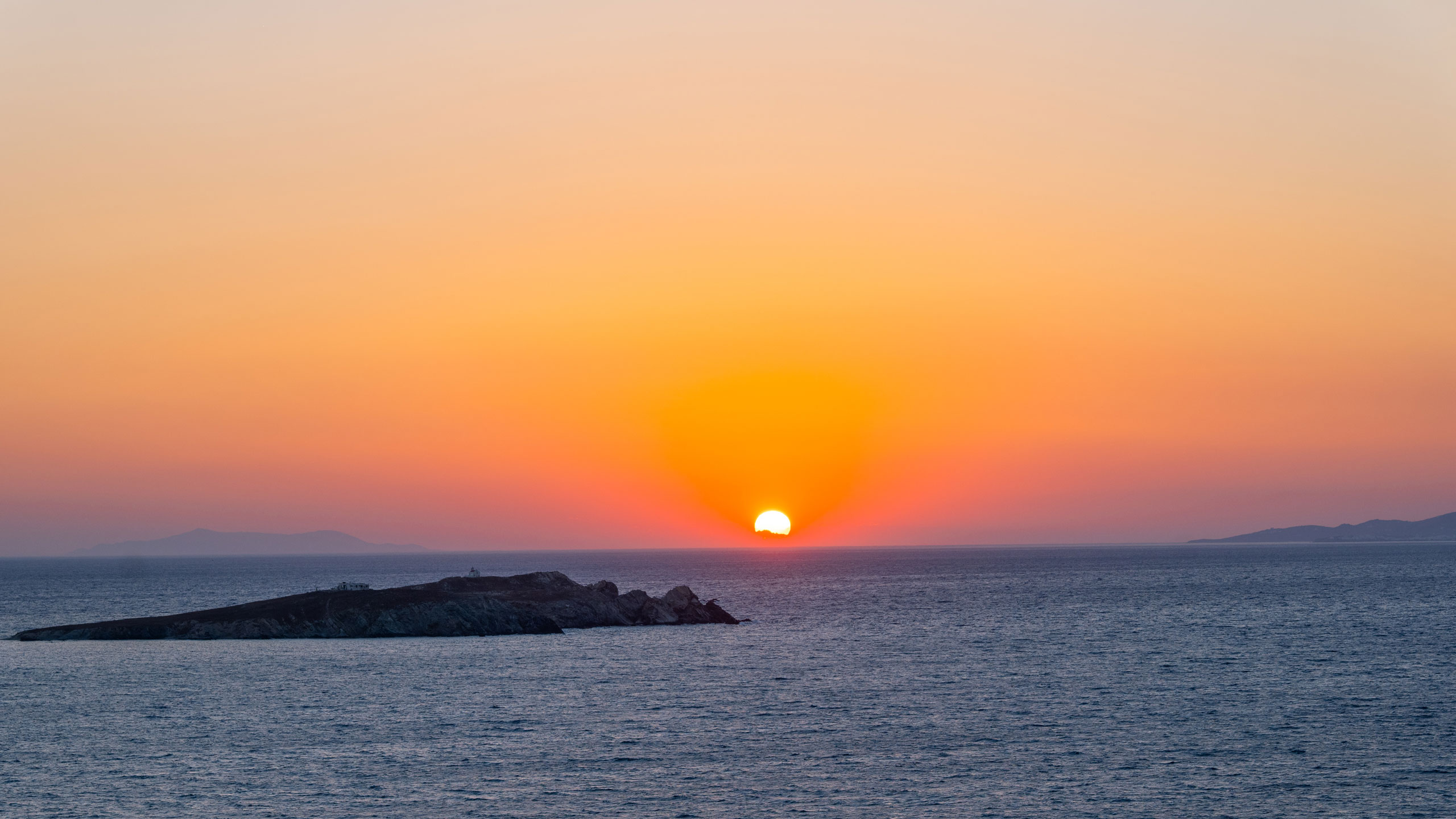 Strandbild mit Sonnenuntergang, Himmel im orangenen Licht und Meer im Vordergund